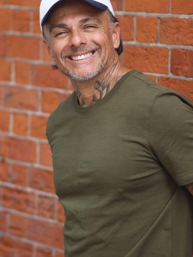 George laughing in front of a brick wall