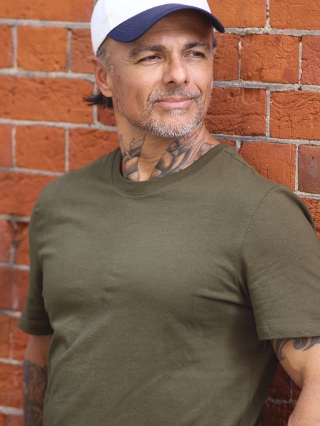 George smiling in front of a brick wall